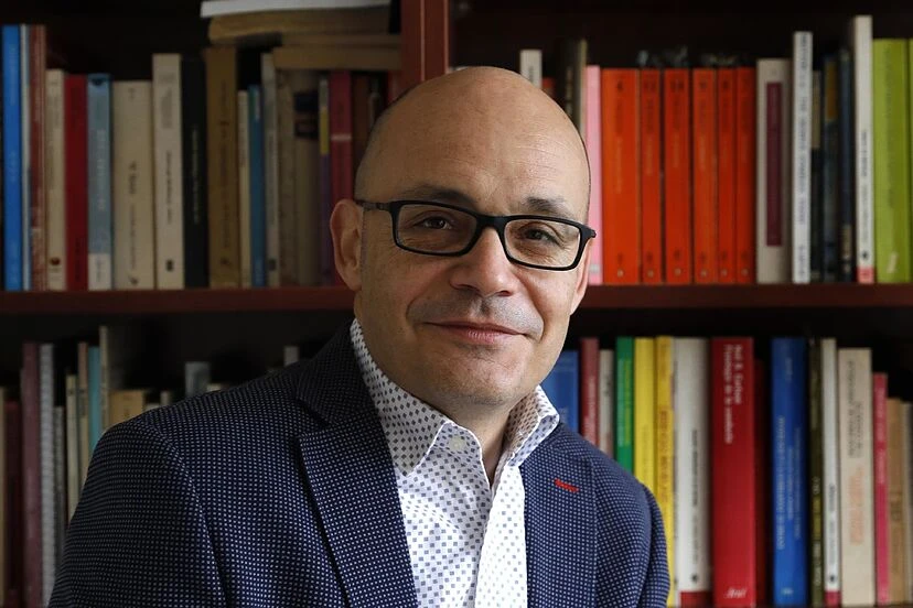 Miguel Perlado, psicólogo experto en sectas, sonriendo delante de una estantería con libros