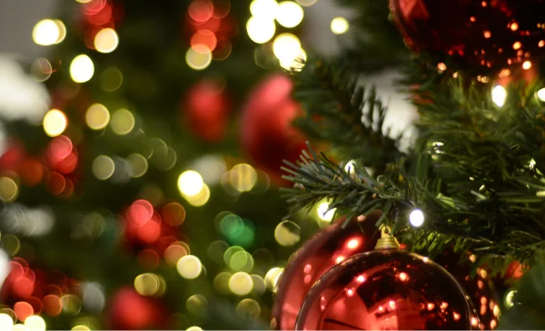 Primer plano de un árbol de Navidad con bolas rojas y luces desenfocadas.